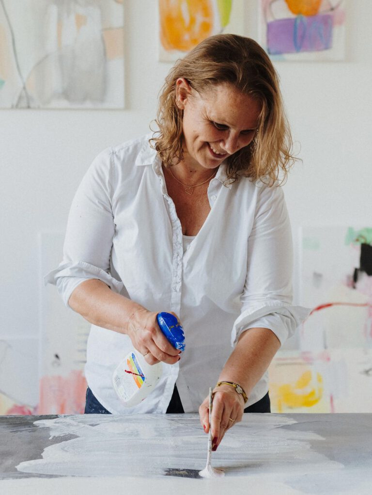 pia staßen mit Pinsel und Spritzflasche an der Leinwand im Atelier