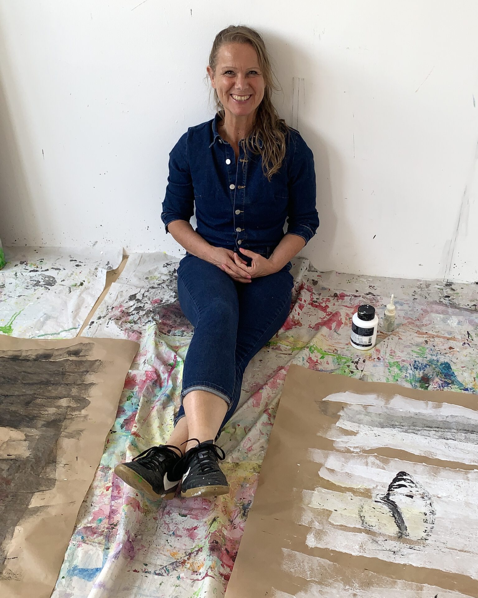 pia staßen mit Freude im Atelier auf dem Boden sitzend